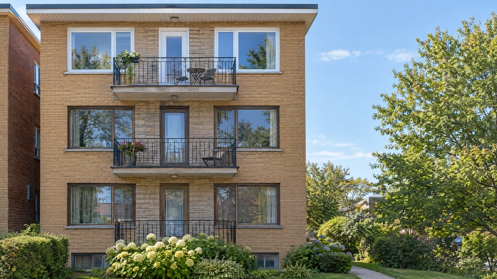 Brick triplex façade with new windows on the upper floors and older original windows still on the ground floor